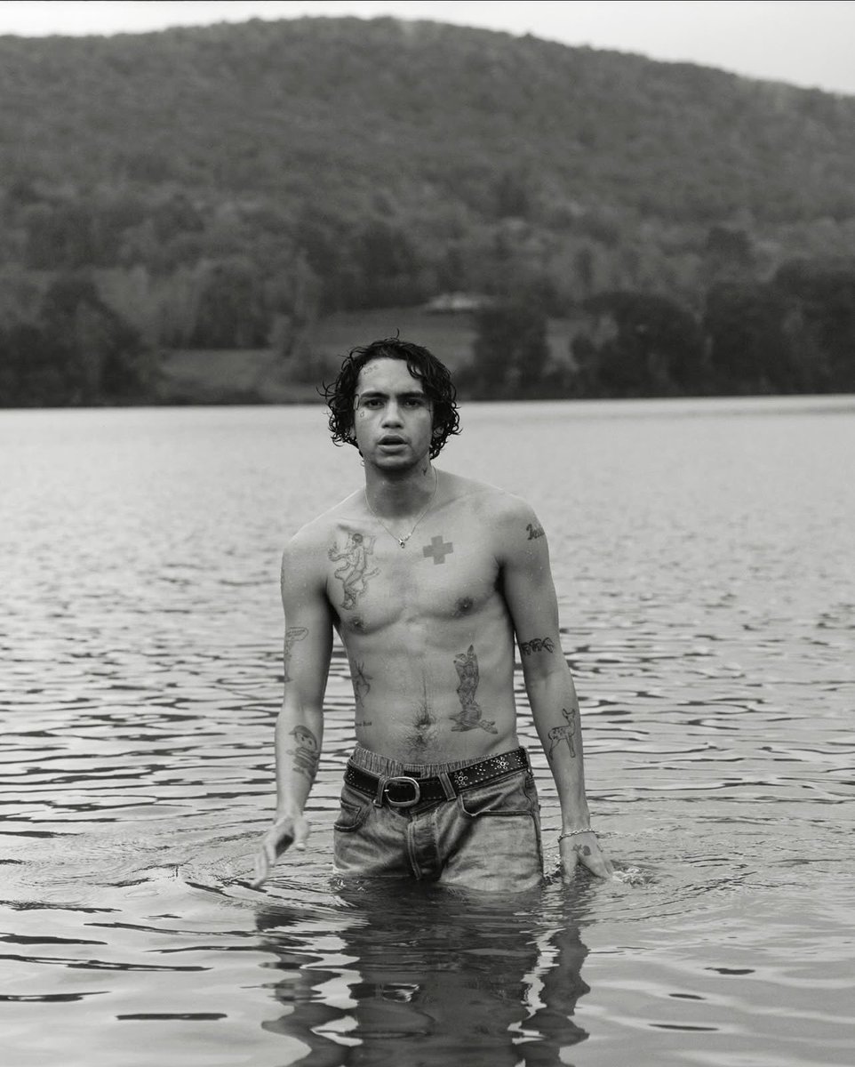 Dominic Fike tattoos: chest cross, torso figure, forearms, hands, and asymmetrical placement