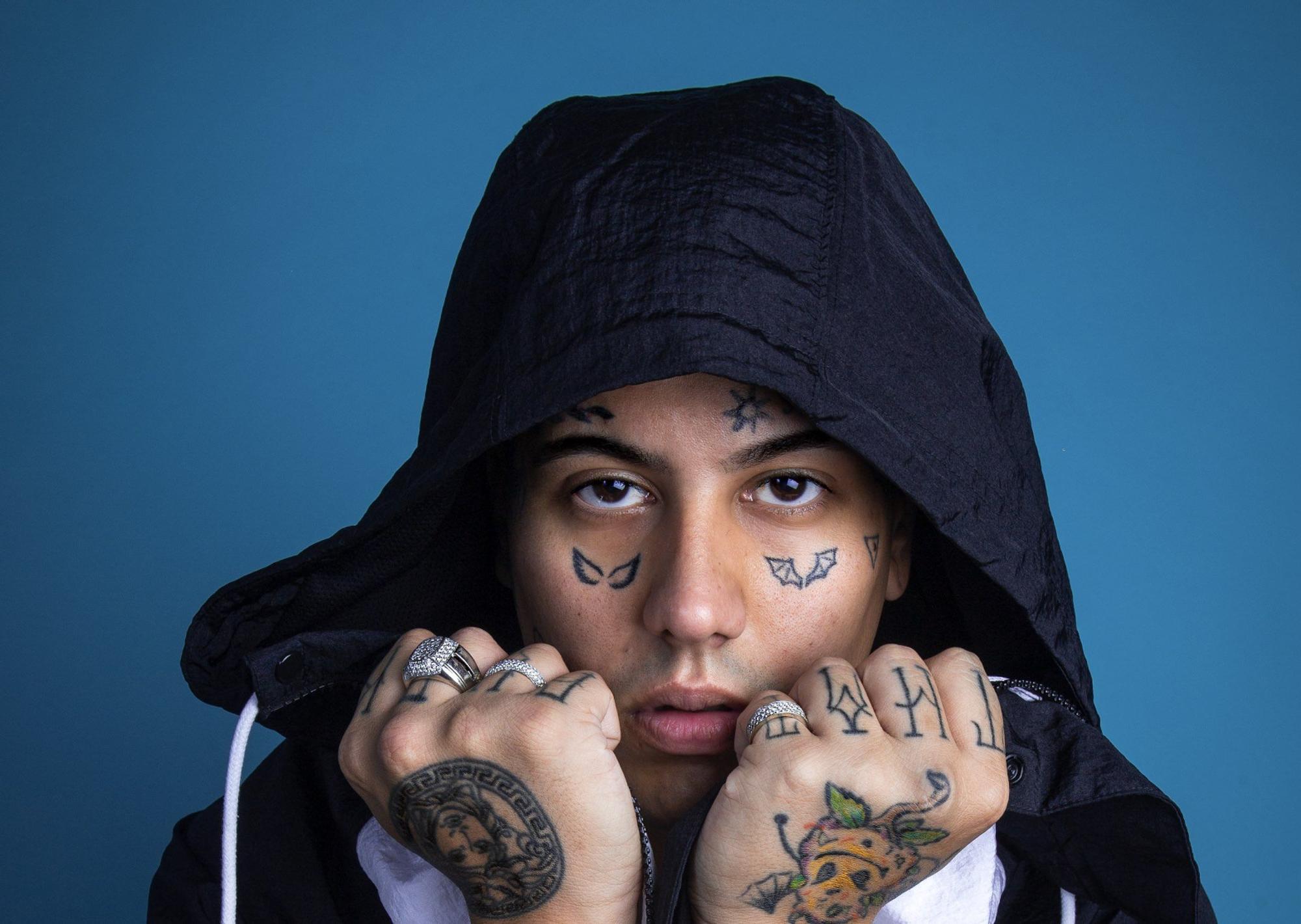 Duki tattoos: Face wings and hand tattoos in a direct portrait