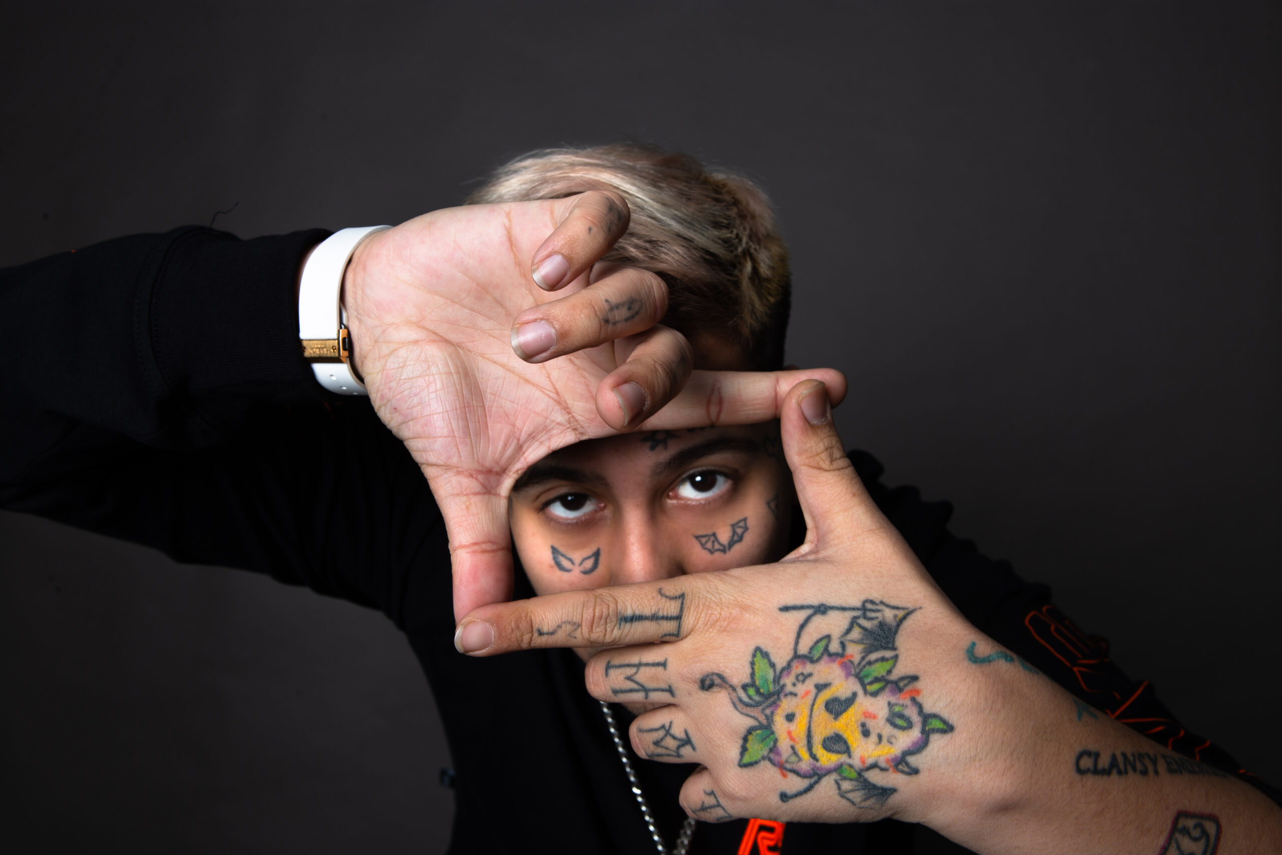 Duki tattoos: Distinct framing pose showing hand and finger tattoos