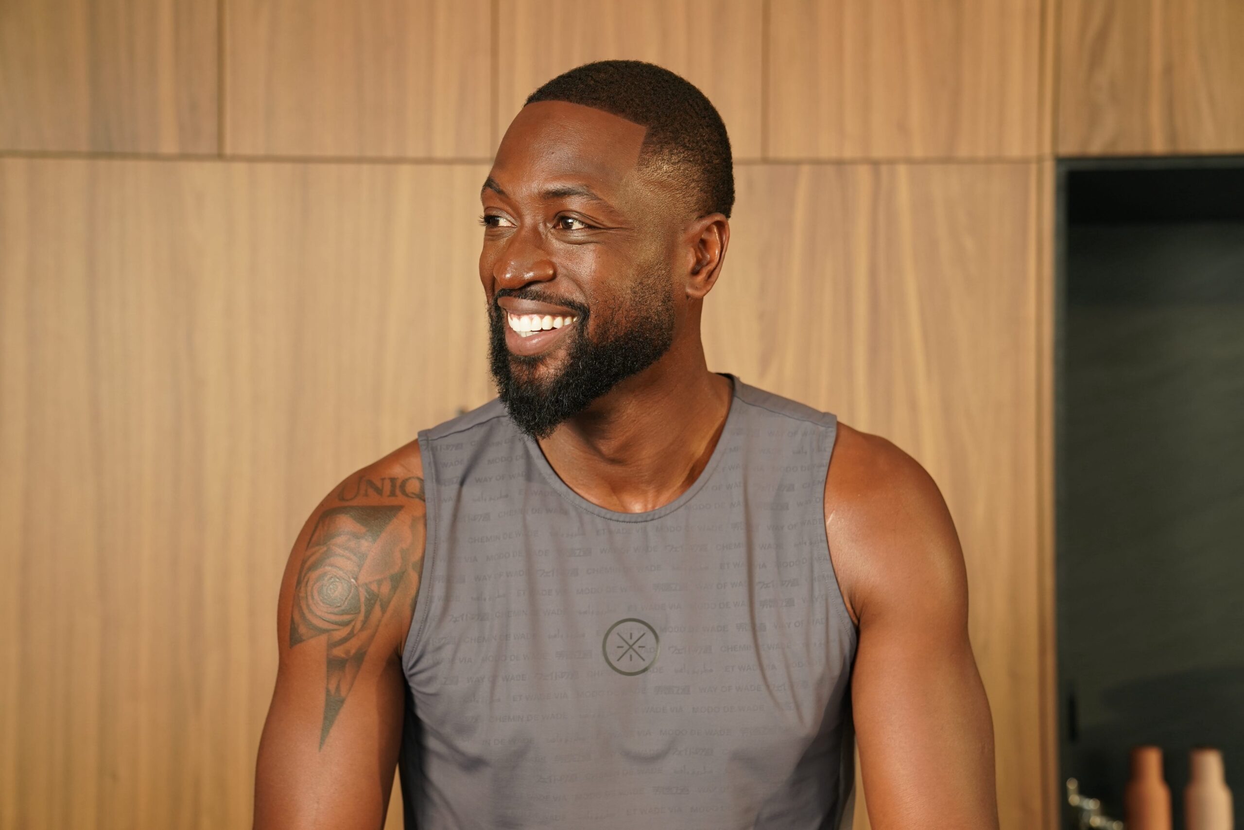 Dwyane Wade tattoos: upper-arm tattoo visible in a relaxed Men’s Health tank-top portrait