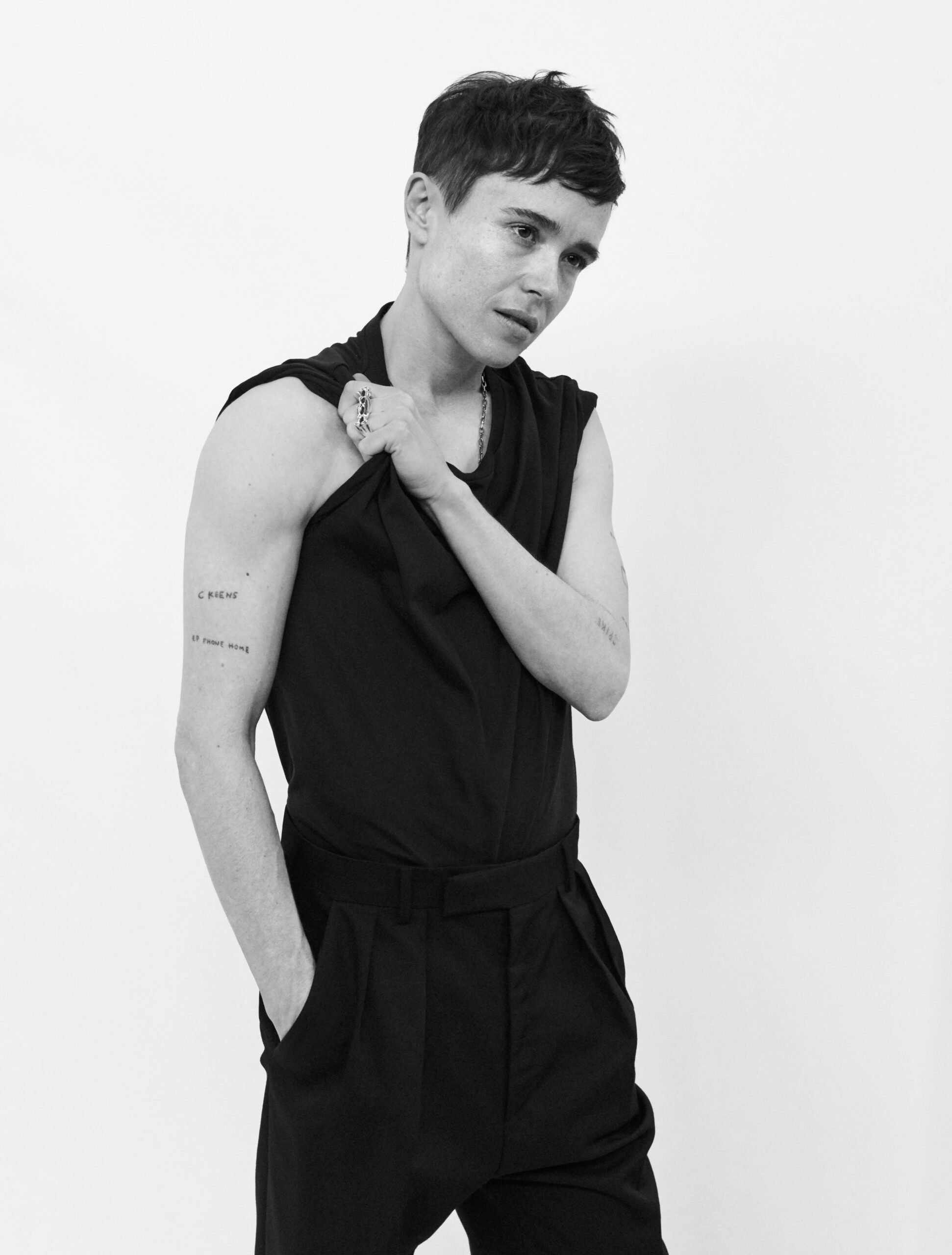 Elliot Page tattoos: Full studio portrait with C KEENS and EP PHONE HOME visible on the right arm