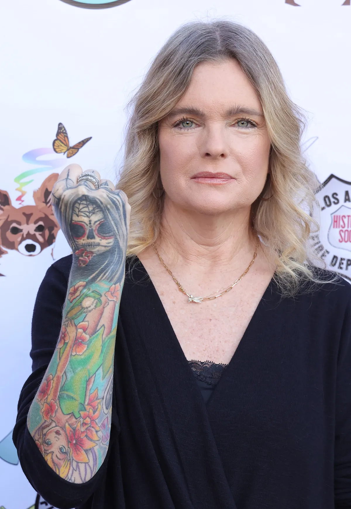 Erika Eleniak tattoos: Close event photograph showing the skull, flowers and bright lower-arm color