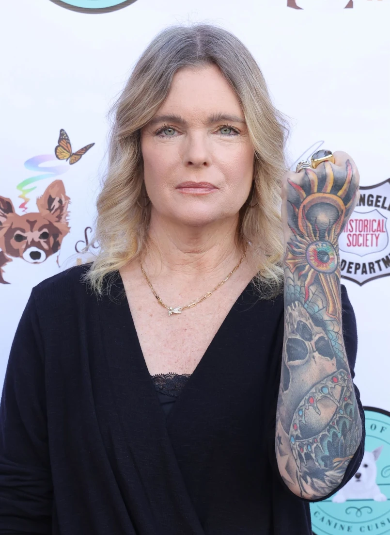 Erika Eleniak tattoos: Close view of the raised arm, eye-like design, skull, flowers and colorful sleeve