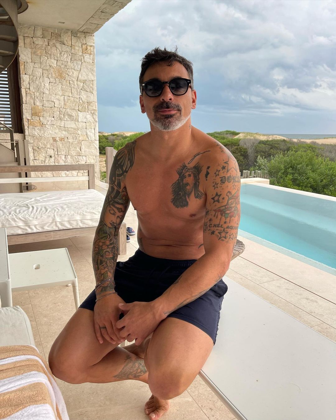 Ezequiel Lavezzi tattoos: natural-light pool portrait showing chest, shoulder and side tattoo placement