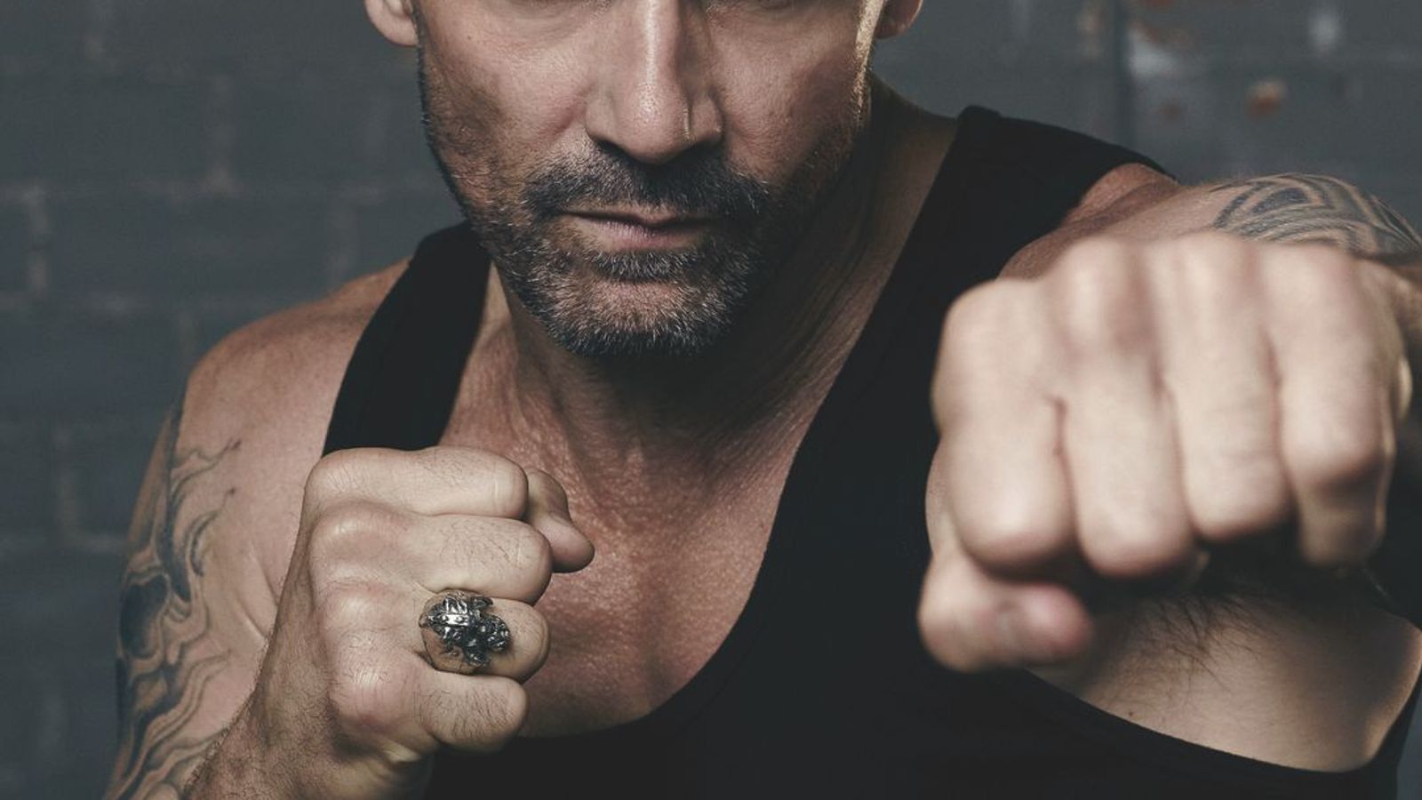 Frank Grillo tattoos: high-resolution action portrait showing the shoulder tattoo in motion