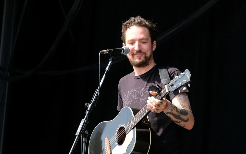 Frank Turner tattoos: Genuine tattoo photograph showing Frank Turner performing with visible arm and hand ink.