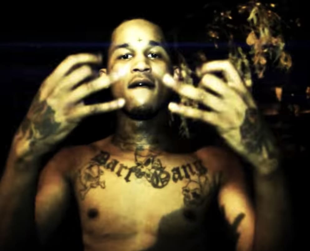 Fredo Santana tattoos: chest, hand and arm tattoos in a dark shirtless portrait