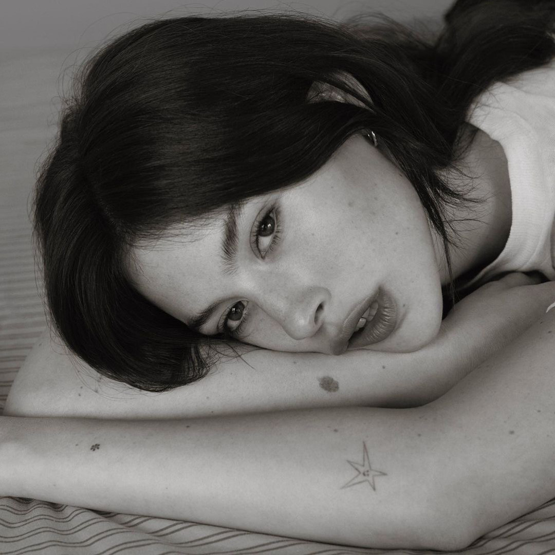 Gracie Abrams tattoos: Black-and-white close-up showing the small outlined star tattoo on Gracie Abrams’ forearm