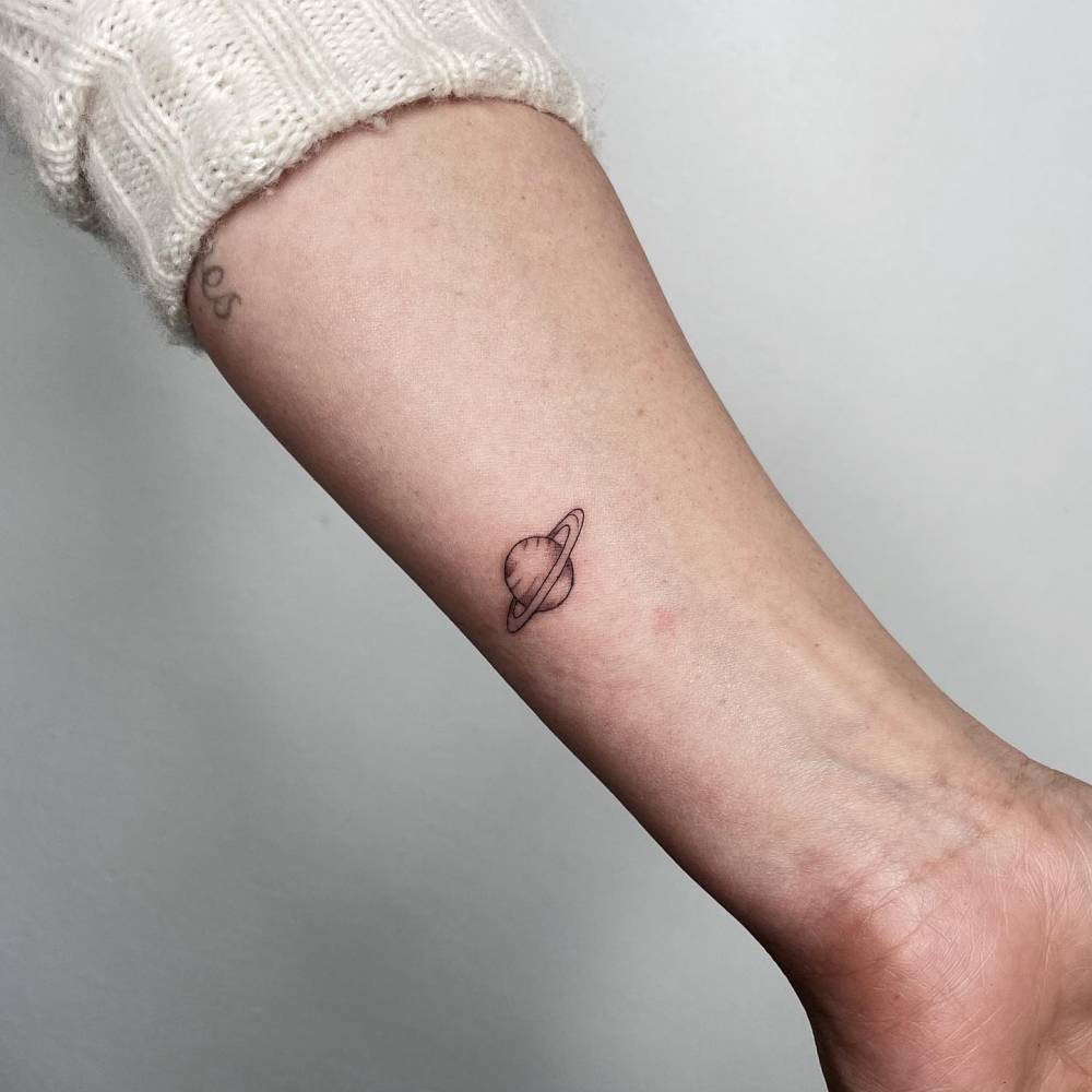 Hilary Duff tattoos: tiny Saturn planet tattoo on the arm