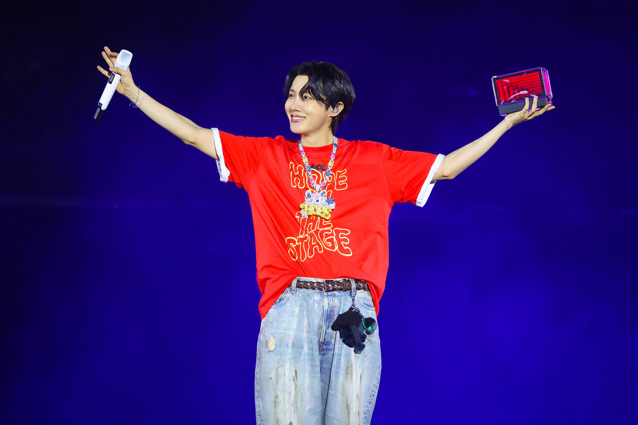 J-Hope in a contextual photograph: concert performance in red tour shirt; contextual photograph, not tattoo evidence; not tattoo evidence