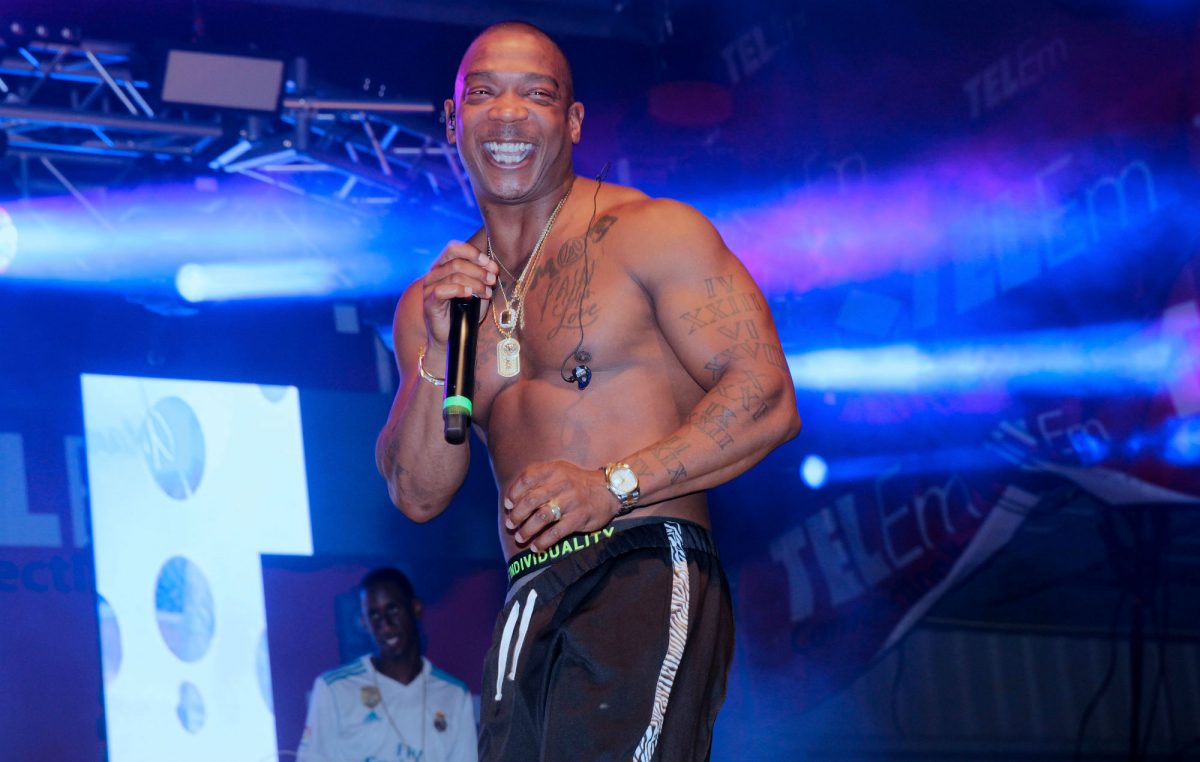 Ja Rule tattoos: high-resolution live photograph showing the arm lettering, Roman numerals and lower torso ink