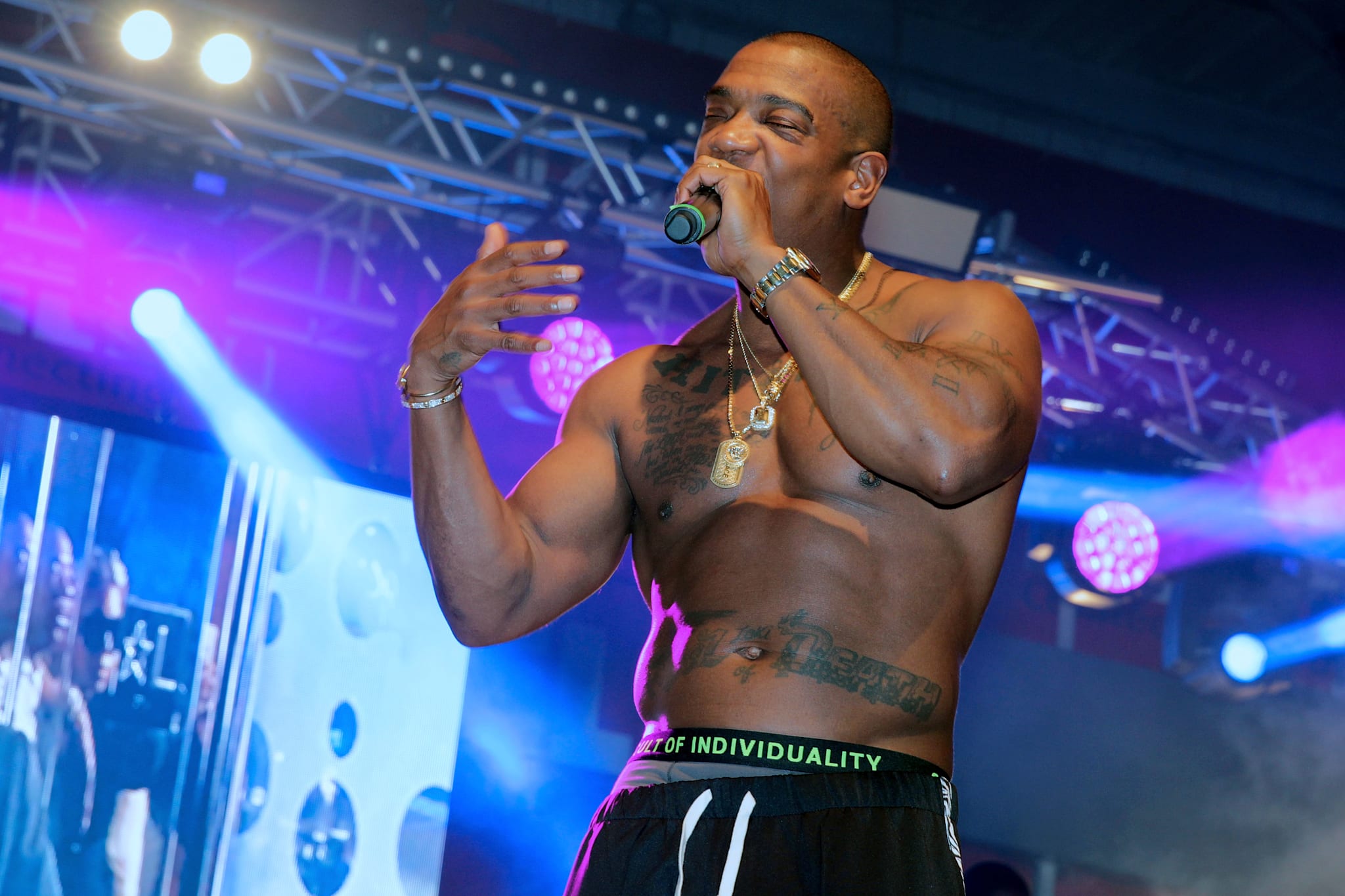 Ja Rule tattoos: high-resolution performance photograph showing the chest, stomach lettering and arm tattoos from a different angle