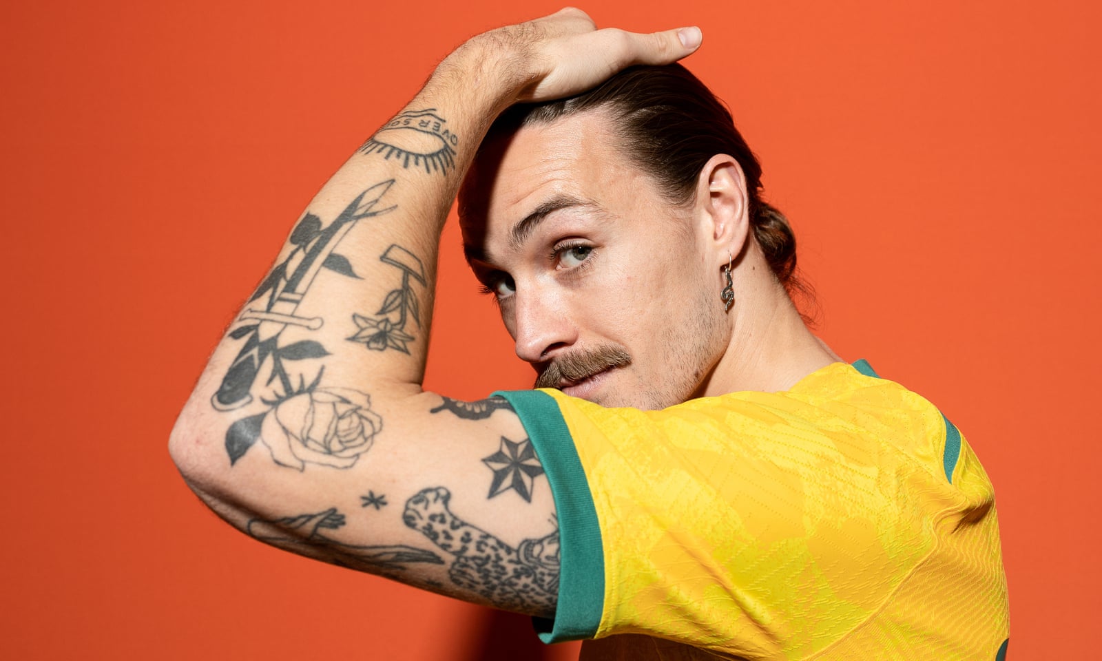 Jackson Irvine Clear close portrait showing floral motifs among the tattoos on Irvine's raised arm; placed with the paragraph about the small flower tattoo he identified as one of his first. Jackson Irvine tattoos: Clear close portrait showing floral motifs among the tattoos on Irvine's raised arm; placed with the paragraph about the small flower tattoo he identified as one of his first.