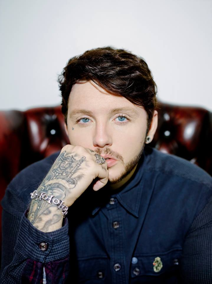James Arthur tattoos: crowned hand tattoo and detailed wrist linework in a close portrait