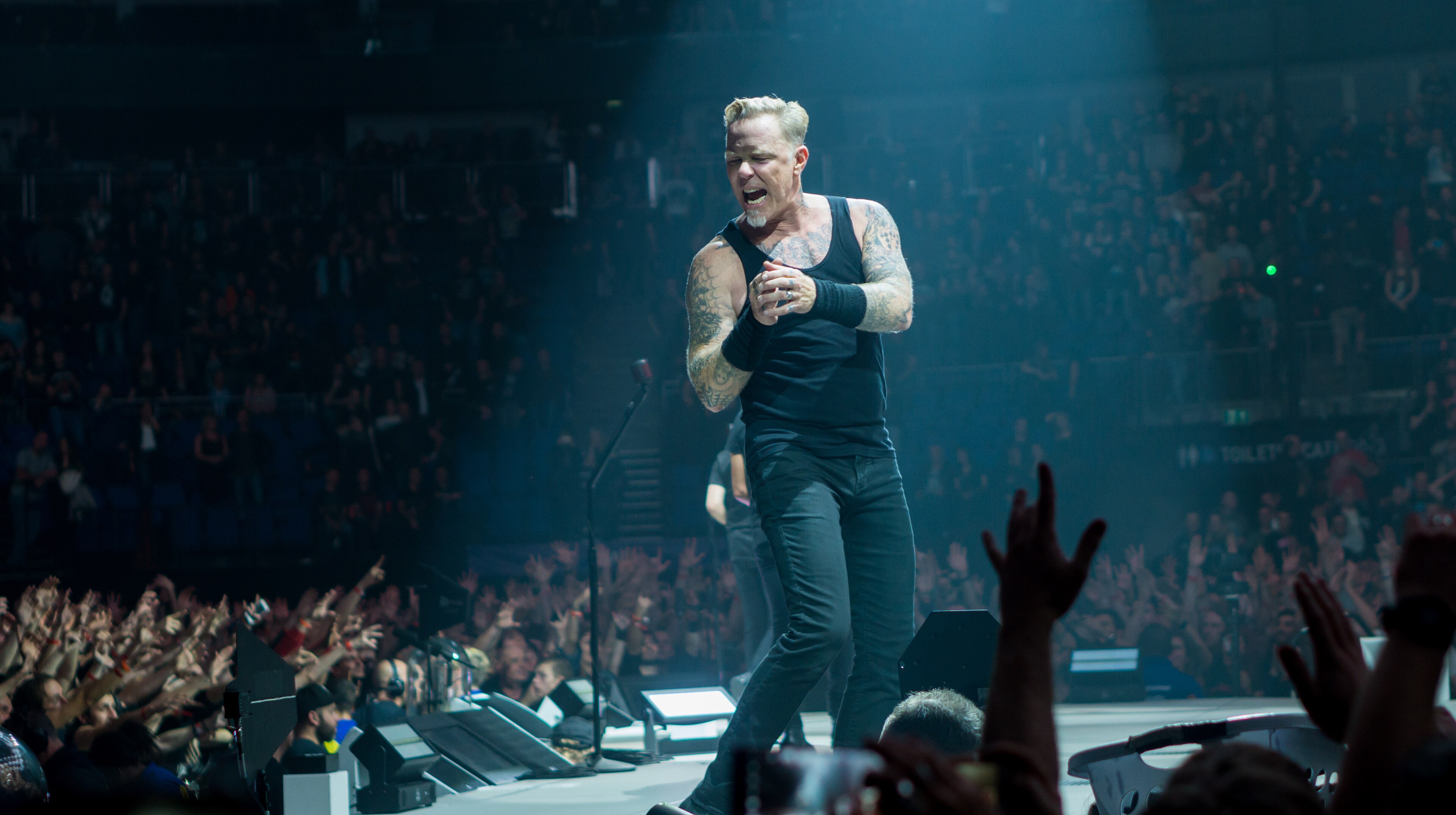 James Hetfield showing chest and shoulder tattoos in a stage photo