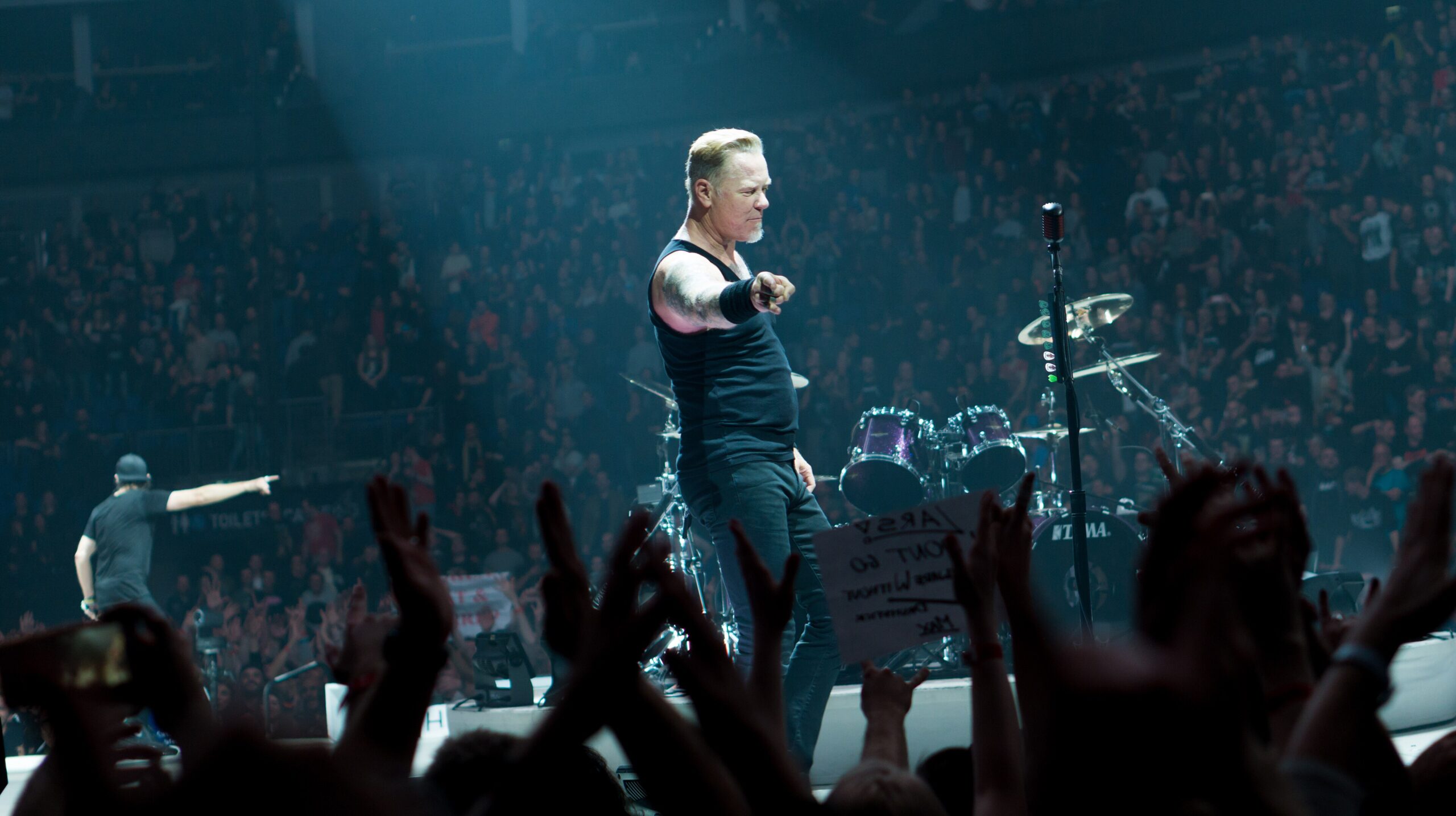 James Hetfield's tattooed arms visible under concert lights