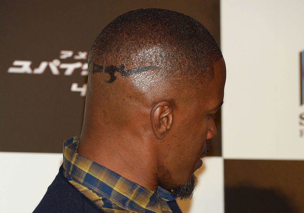 Jamie Foxx tattoos: profile event photograph showing the angular head linework above Foxx’s ear