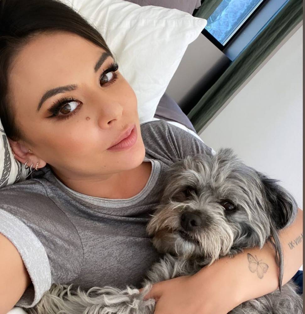Janel Parrish tattoos: small butterfly tattoo visible on the forearm in a face-visible portrait
