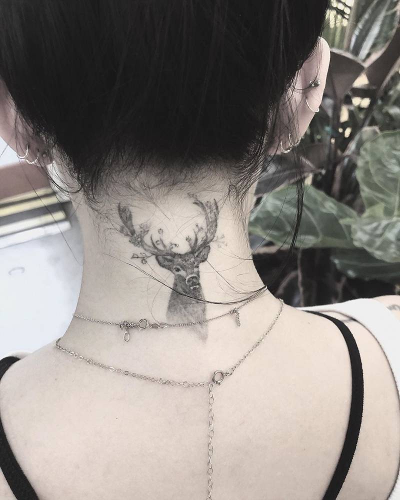 Janel Parrish tattoos: small black-and-grey deer head with antlers at the nape