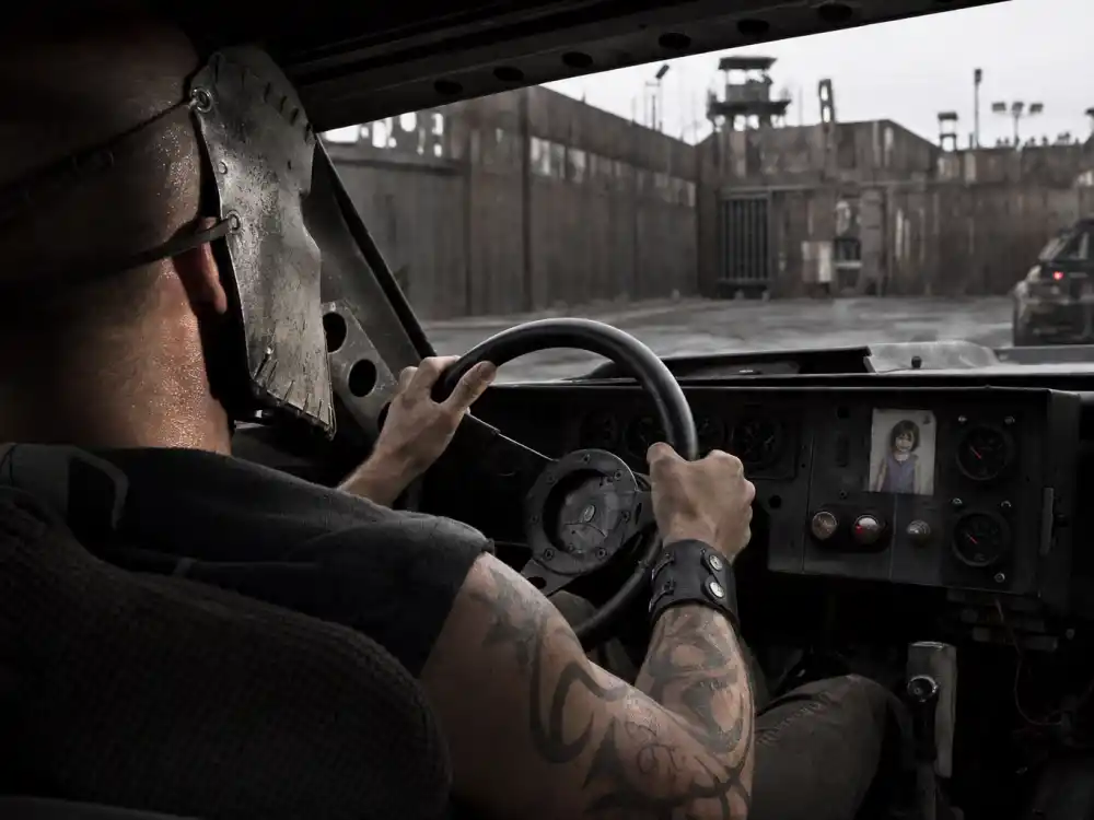Jason Statham tattoos: Death Race driving scene with tattooed forearms visible beneath the Frankenstein mask