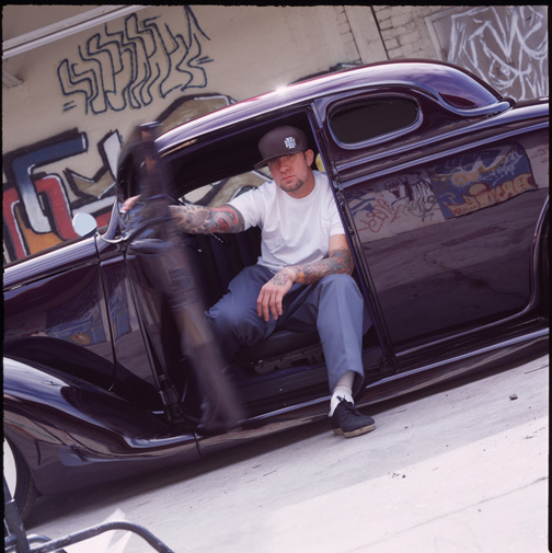 Jesse James tattooed arms beside a car