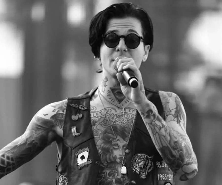 Jesse Rutherford tattoos: Black-and-white performance photograph shows the throat eye, upper-chest lettering and tattooed arms in a clear front-facing view.