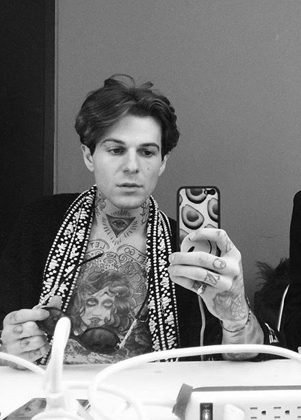 Jesse Rutherford tattoos: Mirror photograph shows the chest portrait, throat symbol, finger marks and the way the tattoos continue toward the hands.