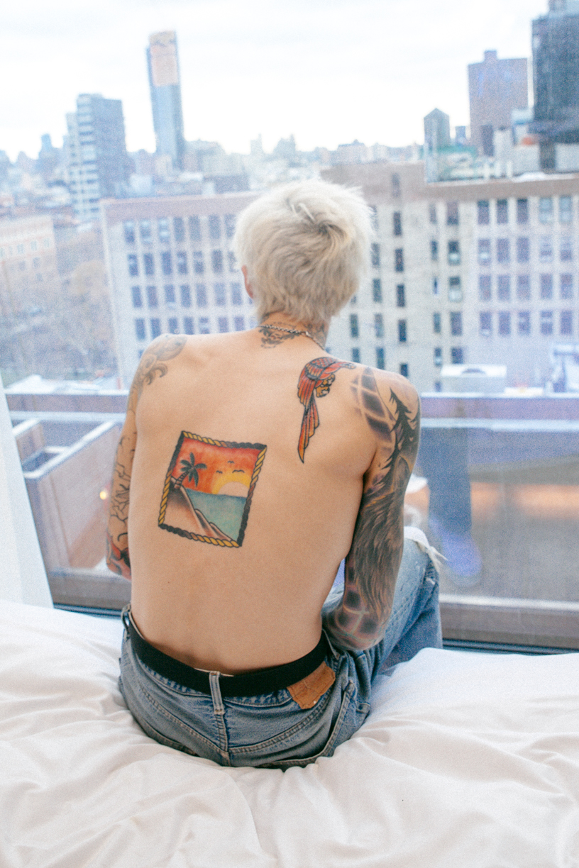 Jesse Rutherford tattoos: Office Magazine back portrait clearly shows the framed orange-and-blue landscape and separate shoulder tattoo work.