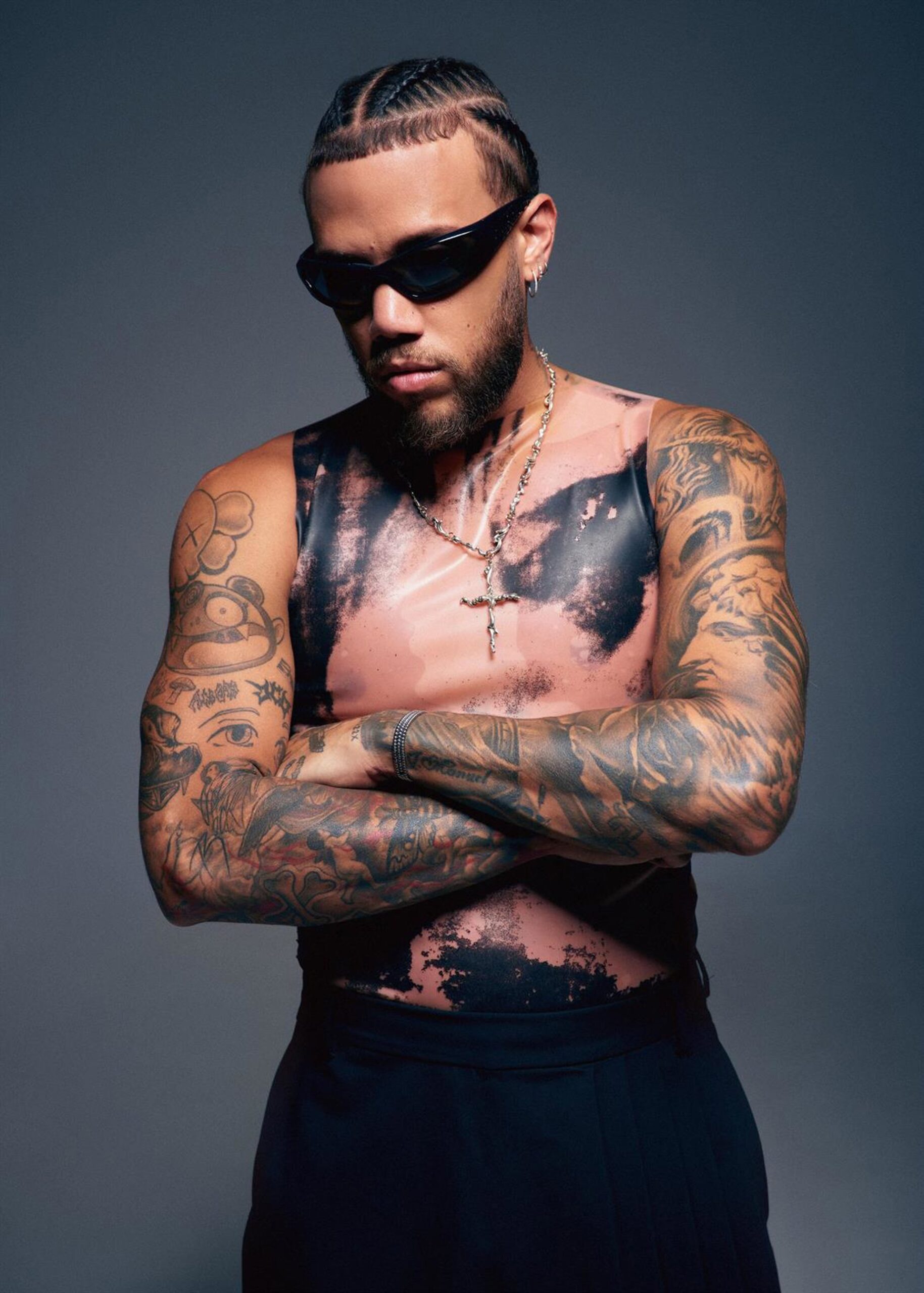 Jhayco tattoos: Festival portrait showing the upper arms, shoulders and chest tattoos from a different angle.