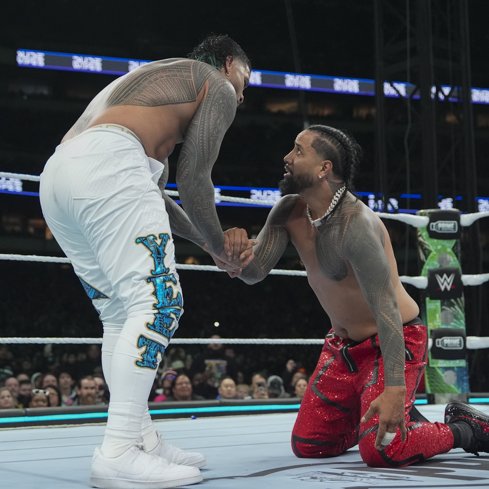 Jimmy Uso tattoos: Left side-neck panel below Jimmy's ear while kneeling in red pants
