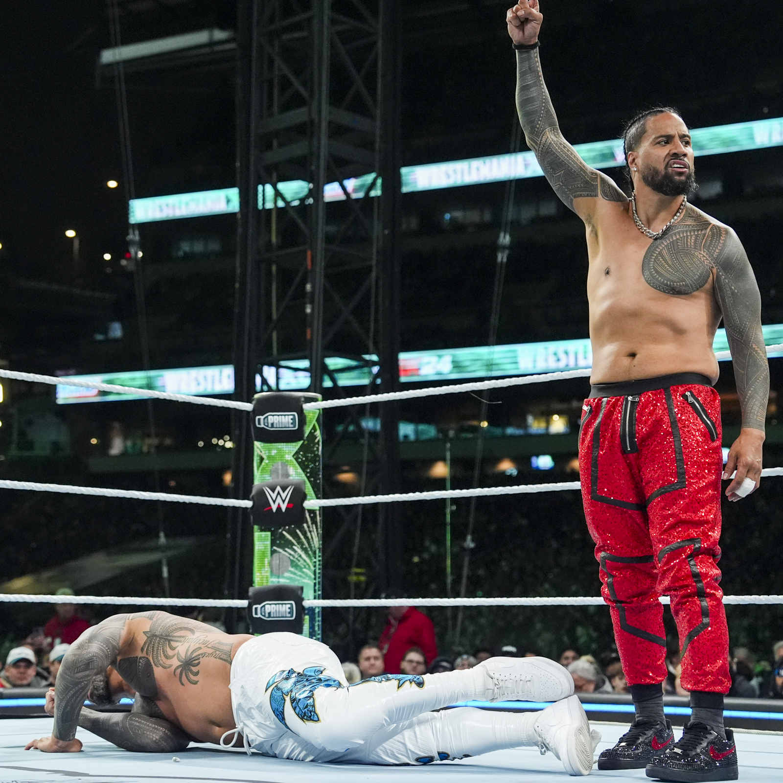 Jimmy Uso tattoos: Right shoulder and upper-arm angular bands while Jimmy raises his arm in red pants