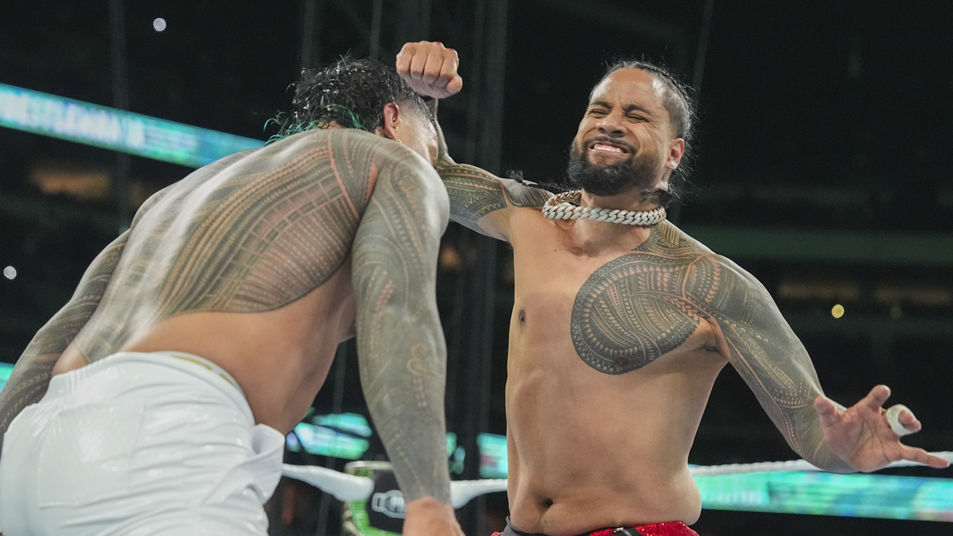 Jimmy Uso tattoos: Rounded left pectoral and collarbone work on Jimmy facing the camera in red pants