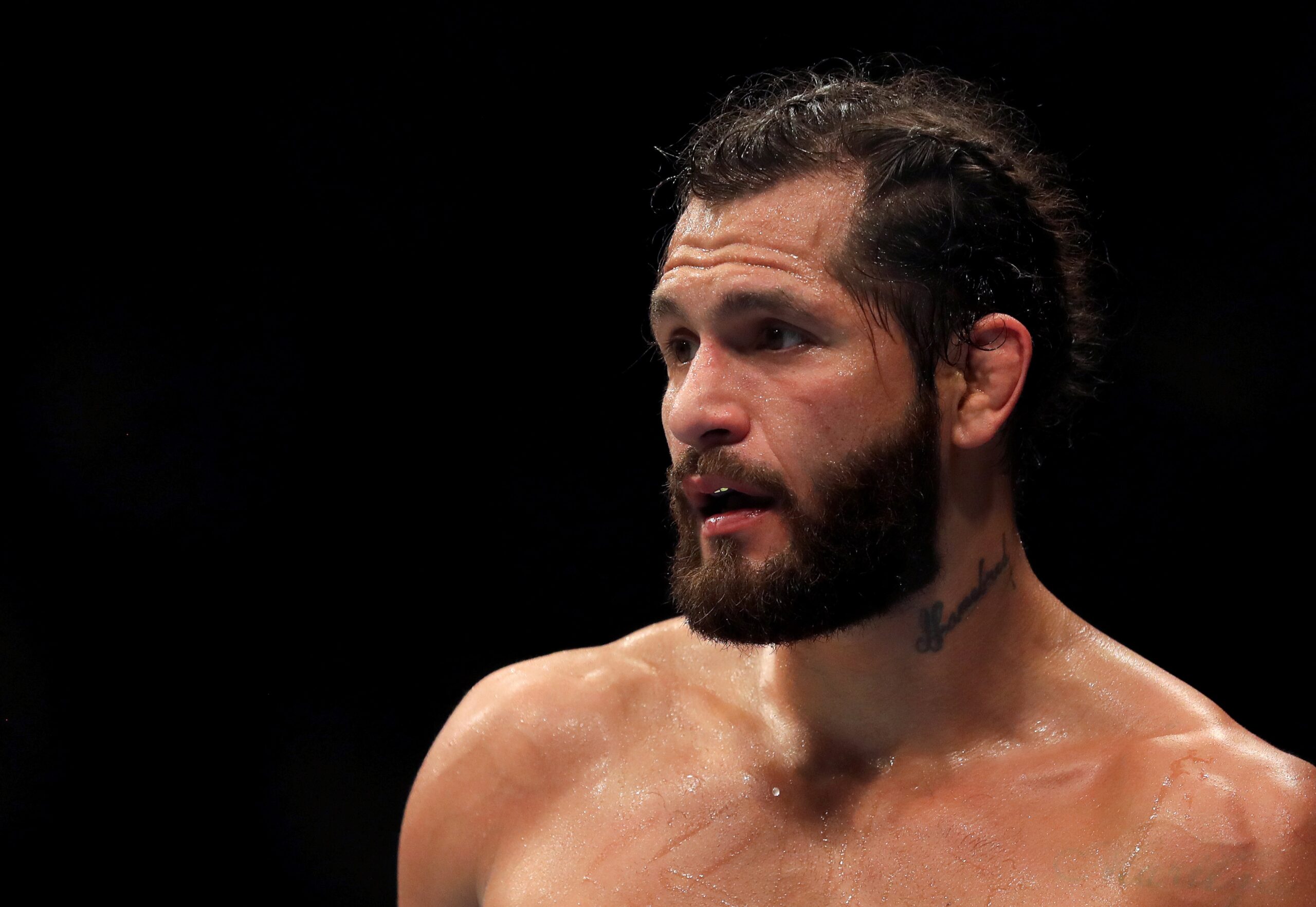 Jorge Masvidal tattoos: distinct dark-background portrait with neck ink visible