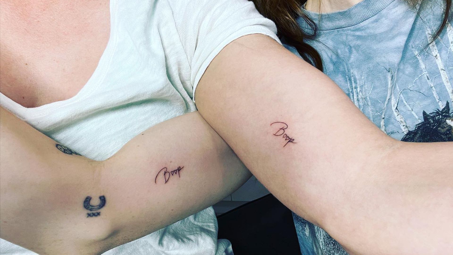 Kaley Cuoco tattoos: Genuine photo of Cuoco and Zosia Mamet raising their arms to display the matching Boop lettering.