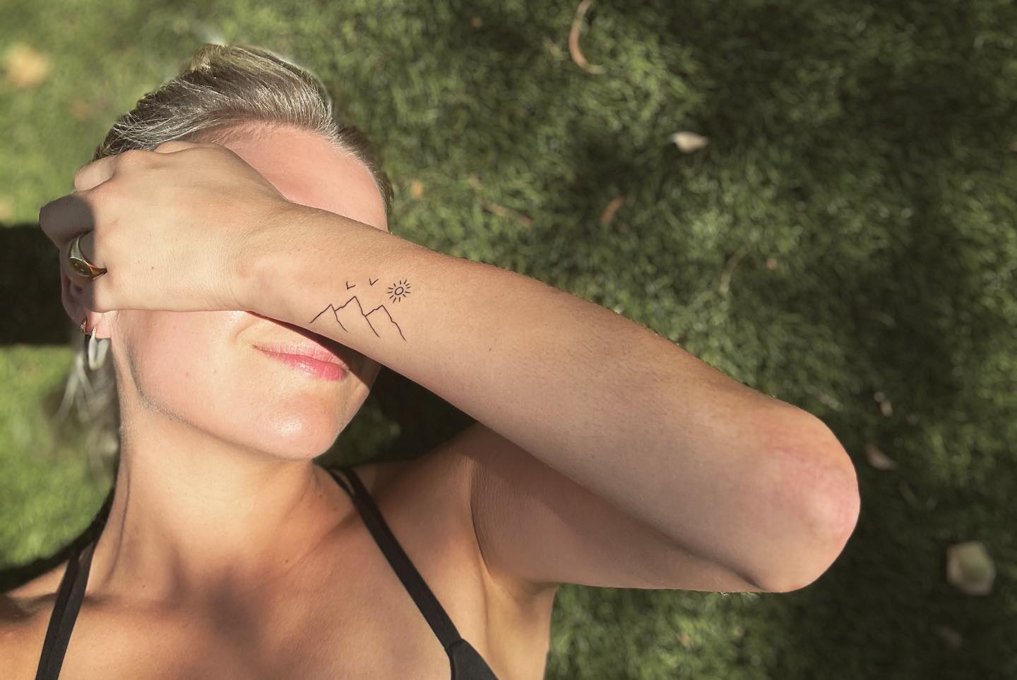 Kelsea Ballerini showing her mountain and birds wrist tattoo