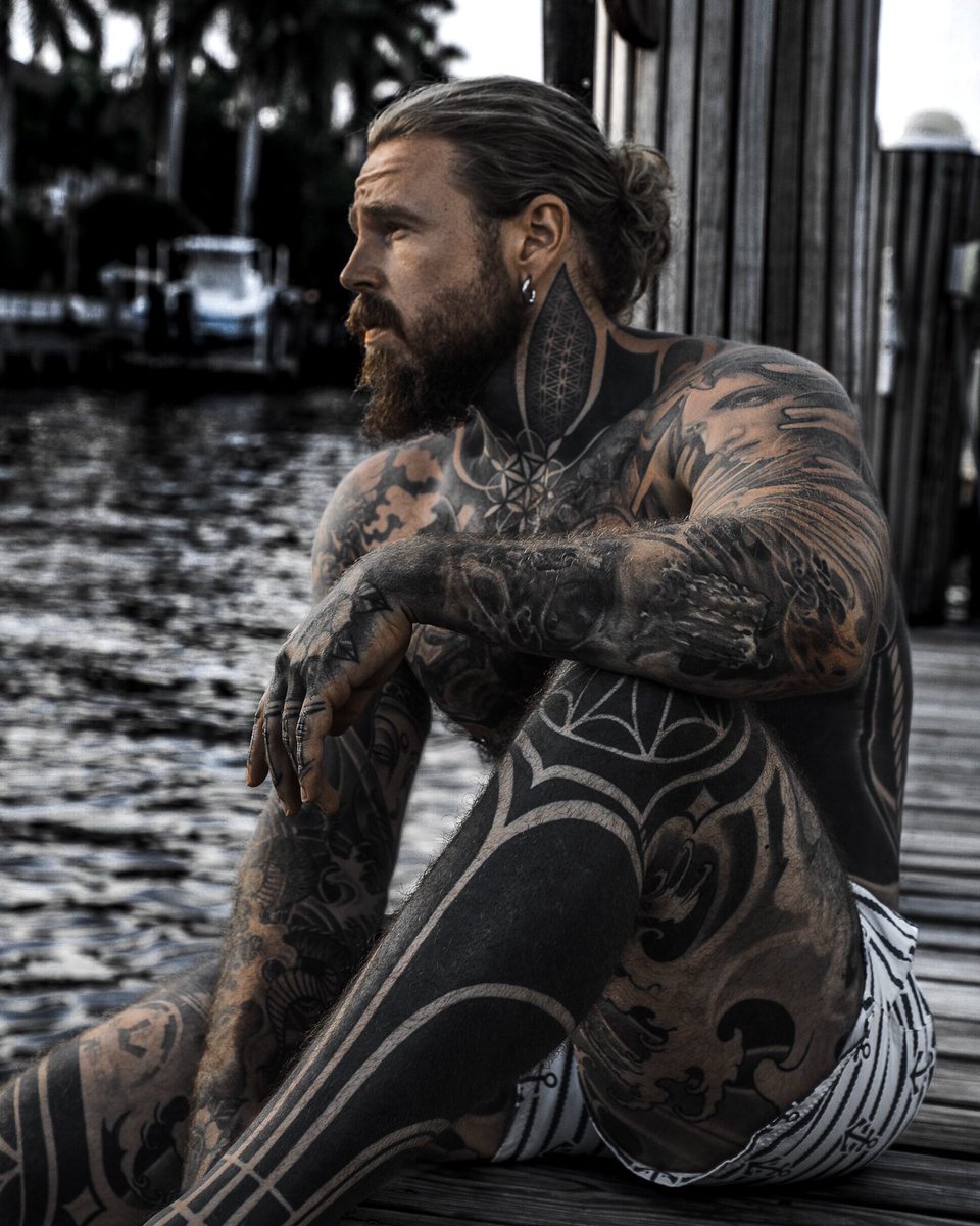 Kevin Creekman tattoos: Broad blackwork leg panels separated by curved open-skin channels