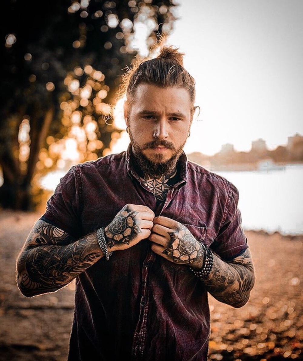 Kevin Creekman tattoos: Paired flower motifs and circular geometry on backs of hands