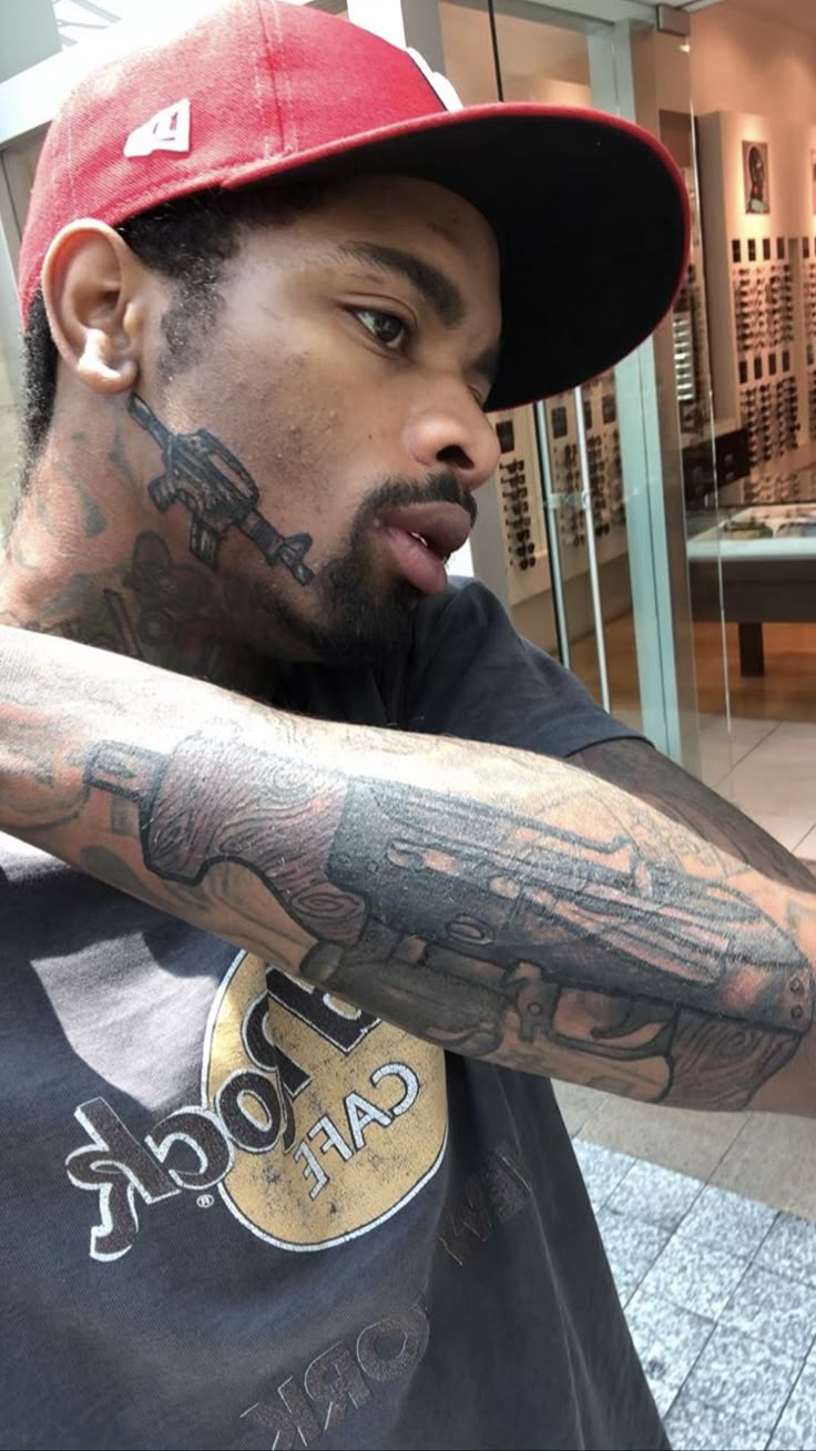 Key Glock tattoos: rifle design on the neck and dense forearm ink