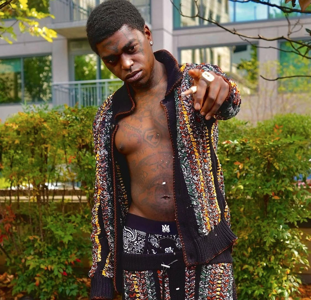 Kodak Black with his chest tattoos visible through an open jacket