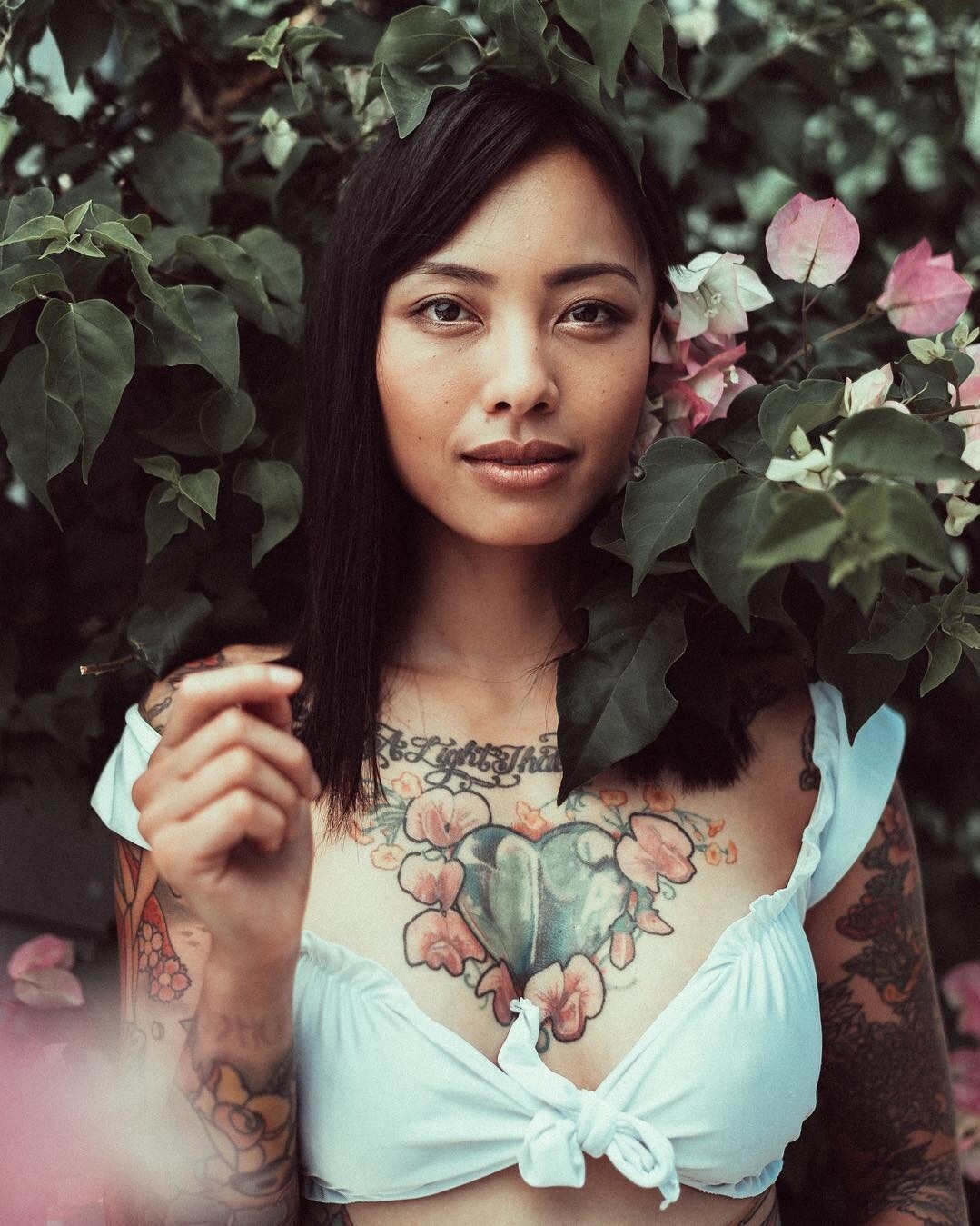 Levy Tran tattoos: Chest heart and both arm tattoos in a close portrait