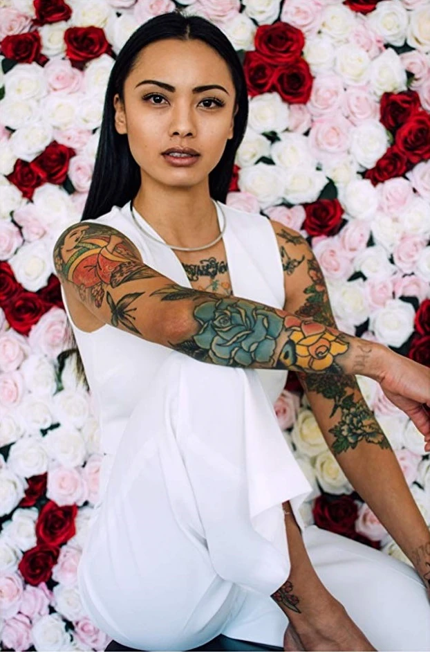 Levy Tran tattoos: Seated view of arm, wrist and lower leg tattoos
