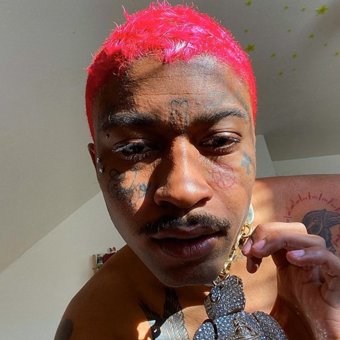 Lil Tracy tattoos: bright red hair, face symbols, chest ink and a large pendant