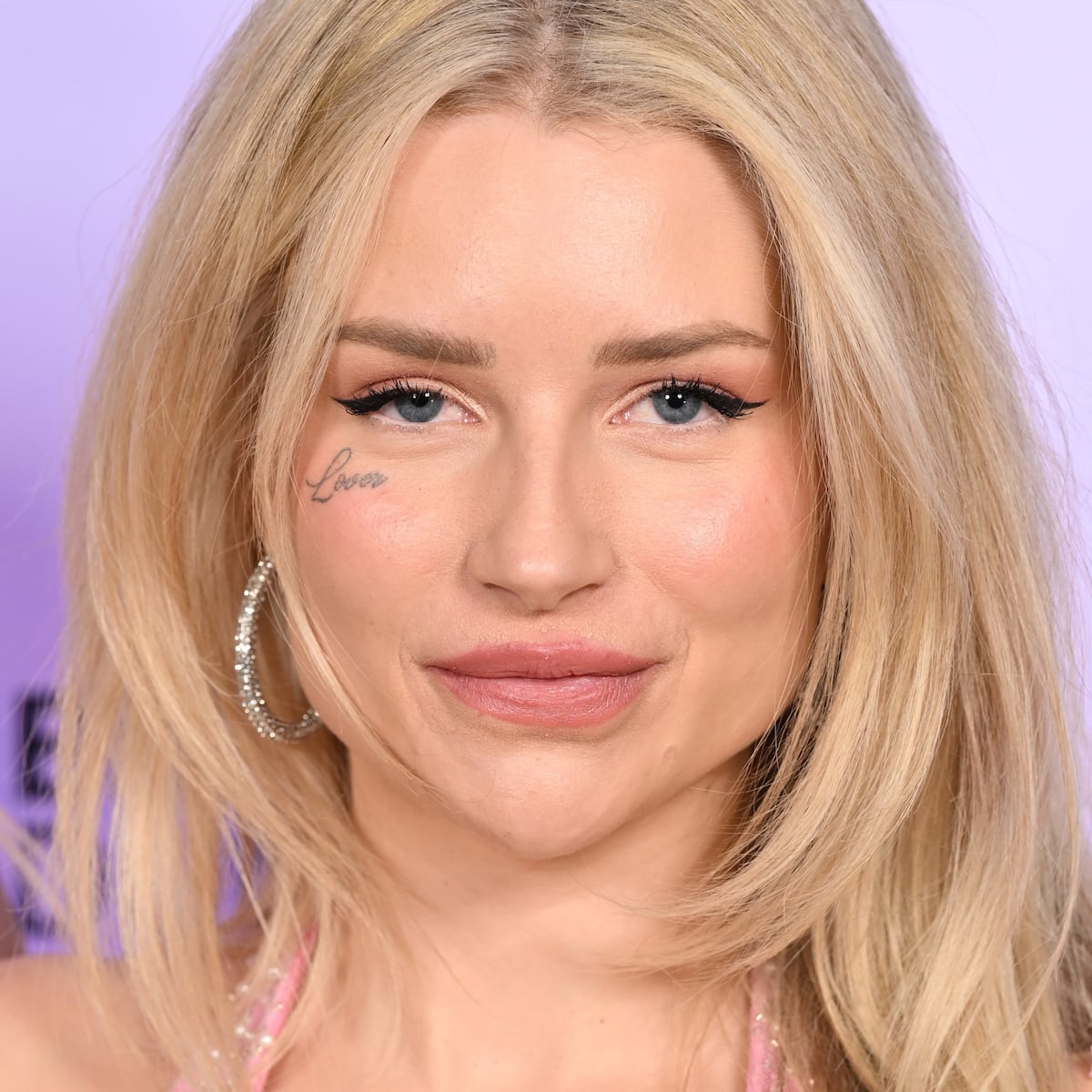 Lottie Moss tattoos: Close face-visible tattoo portrait showing Lottie Moss's Lover tattoo and the surrounding facial placement