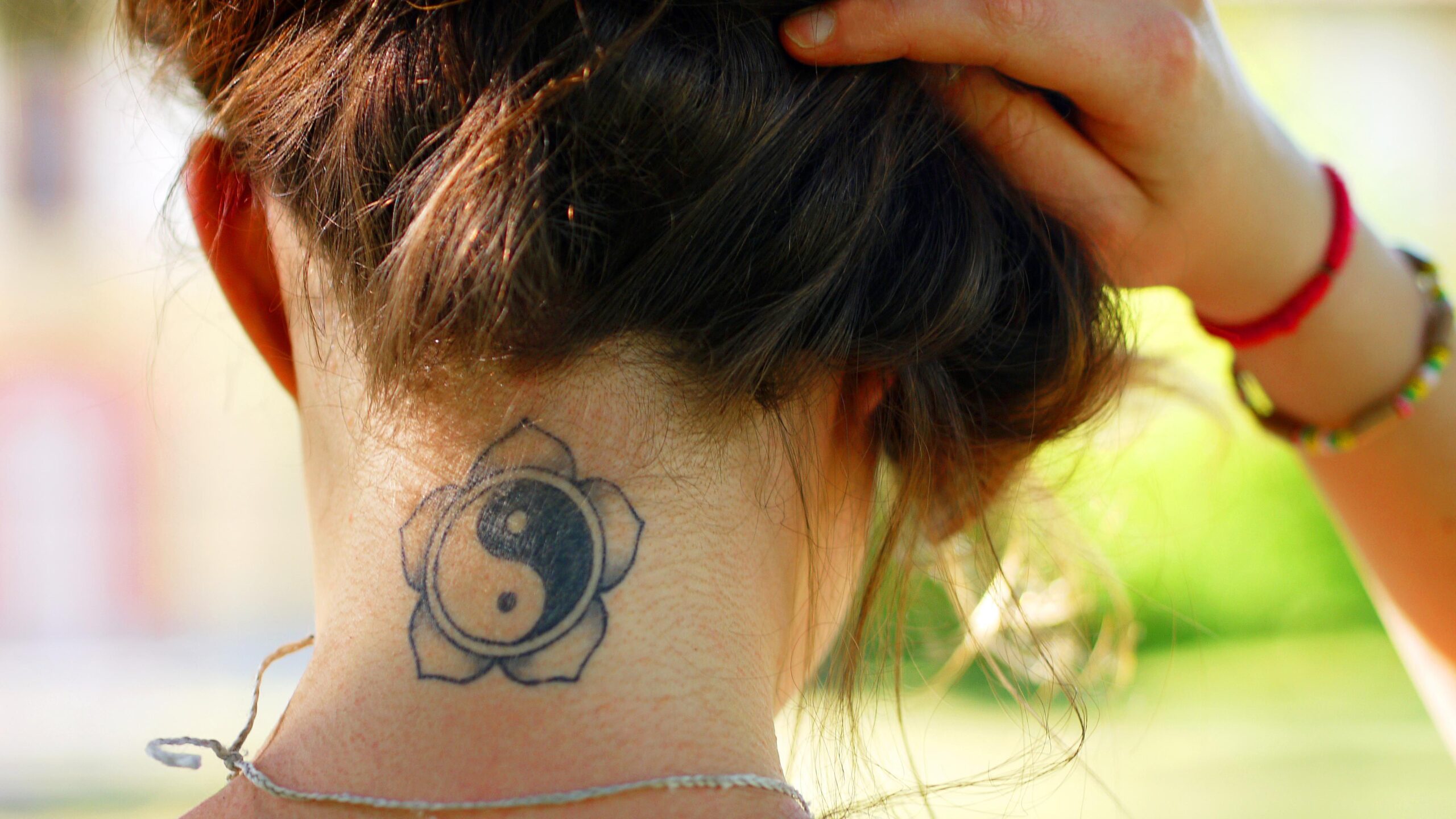Maddie Ziegler yin-yang tattoo inside a rounded floral outline at the nape of her neck.