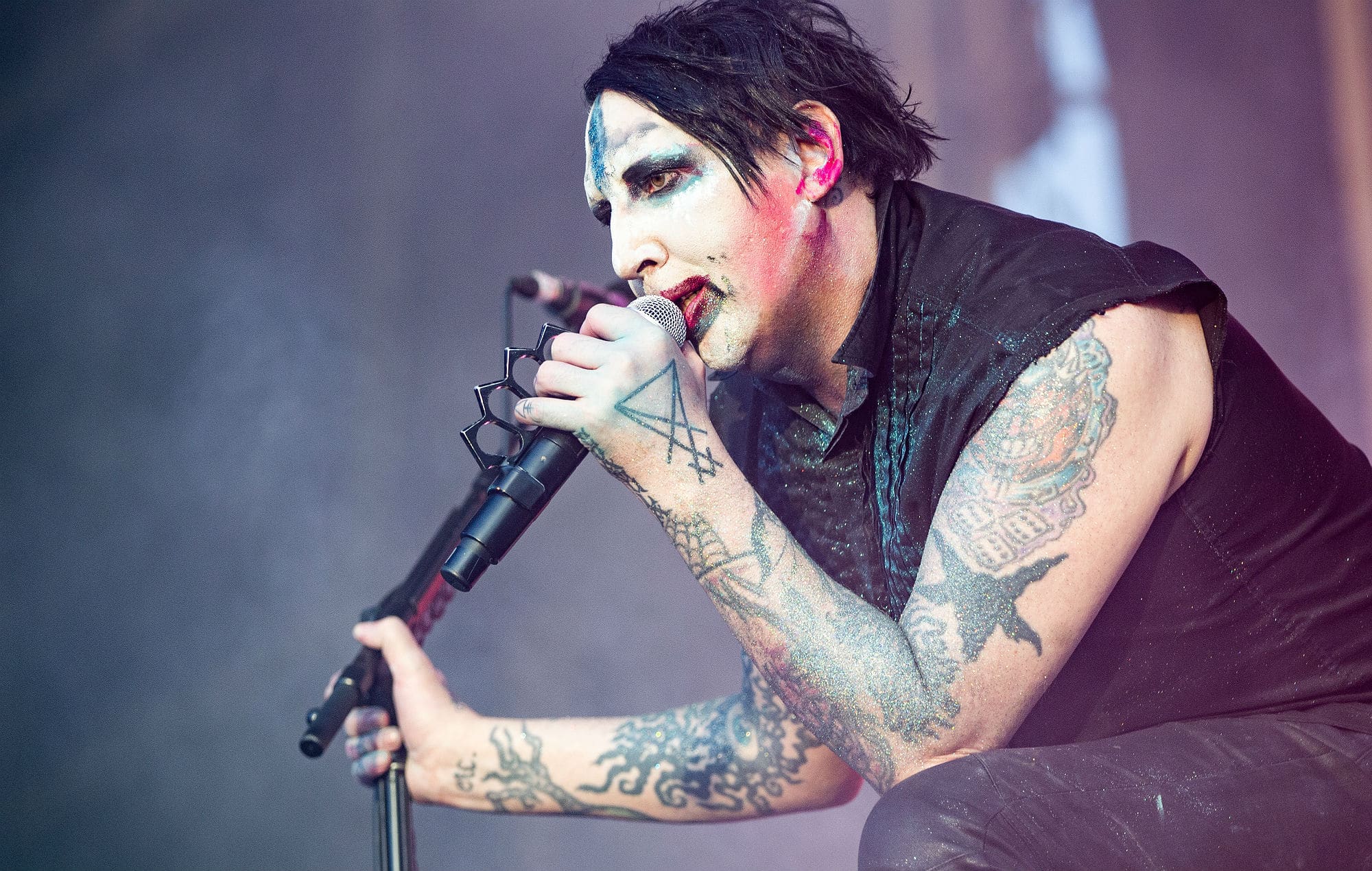 Marilyn Manson tattoos: high-resolution concert photograph showing both tattooed arms and the darker torso pieces