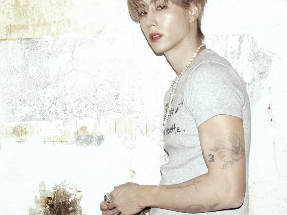 Mark Tuan tattoos: clean high-resolution editorial portrait showing the shaded flower and script along his arm