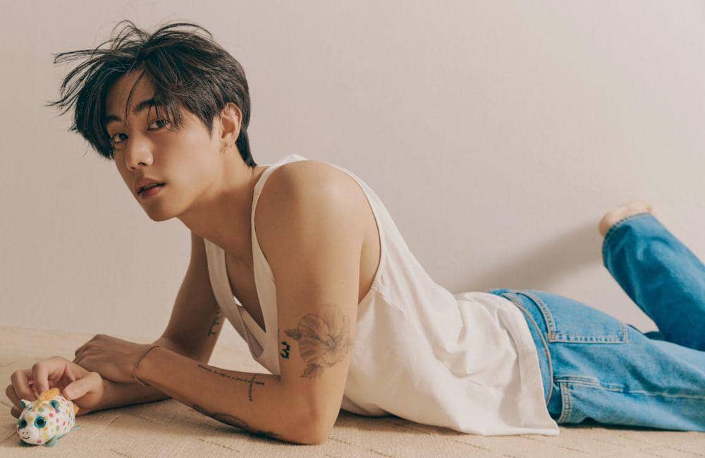 Mark Tuan tattoos: clean high-resolution candid portrait showing the flower, forearm script and smaller arm marks
