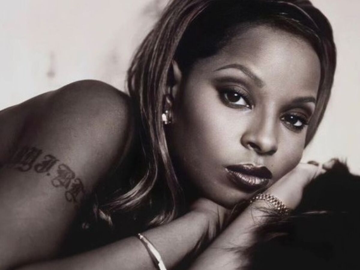 Mary J. Blige tattoos: high-resolution portrait showing the upper-arm lettering and the way shoulder styling changes tattoo visibility