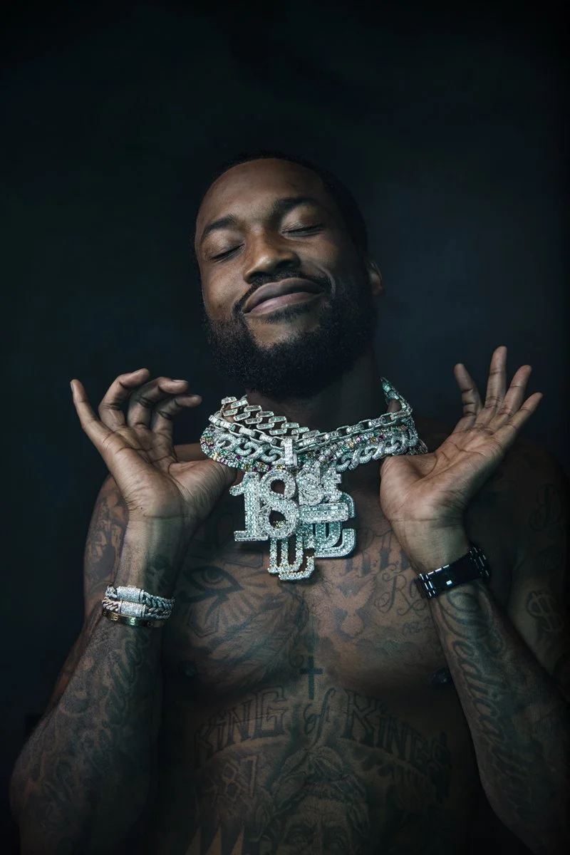 Meek Mill tattoos: front portrait showing the forearms, wrist area and layered chest symbols