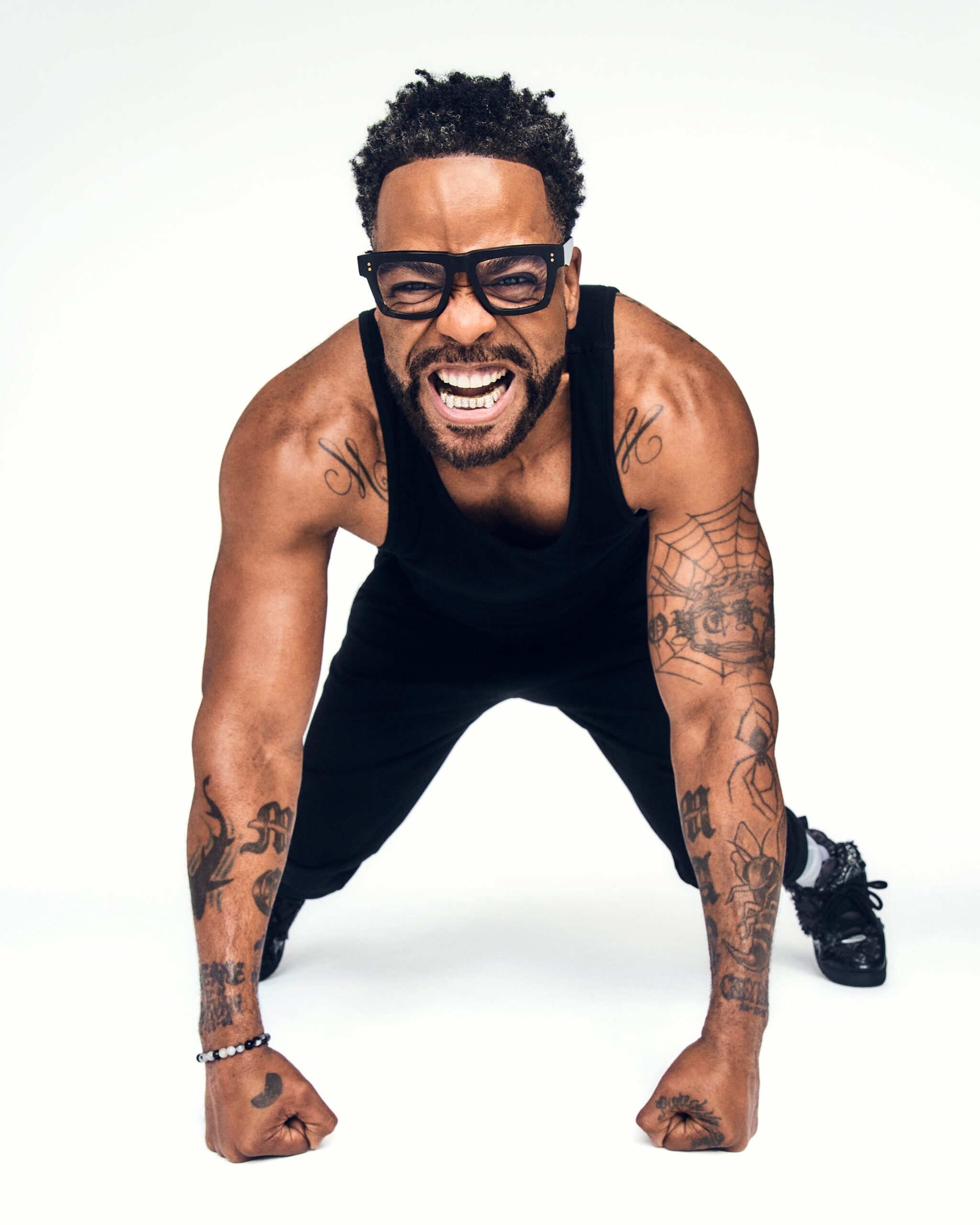 Method Man tattoos: high-resolution portrait with tattooed arms, bold lettering and the spiderweb tattoo visible